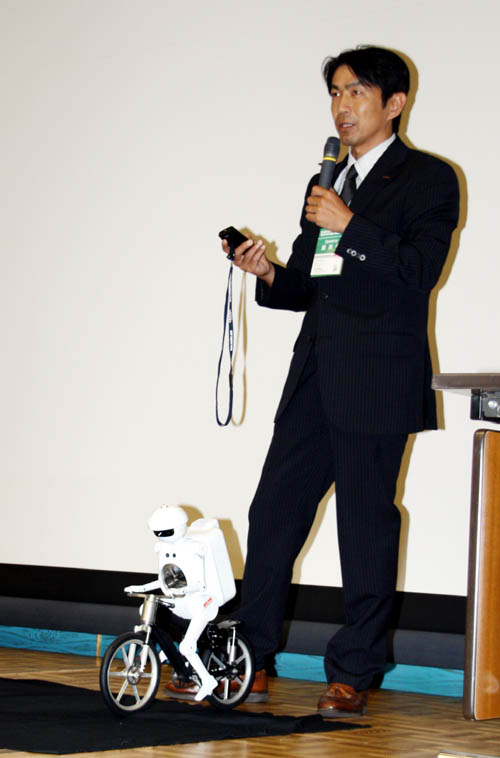 携帯電話によるデモンストレーションを行う吉川浩一氏とムラタセイサク君